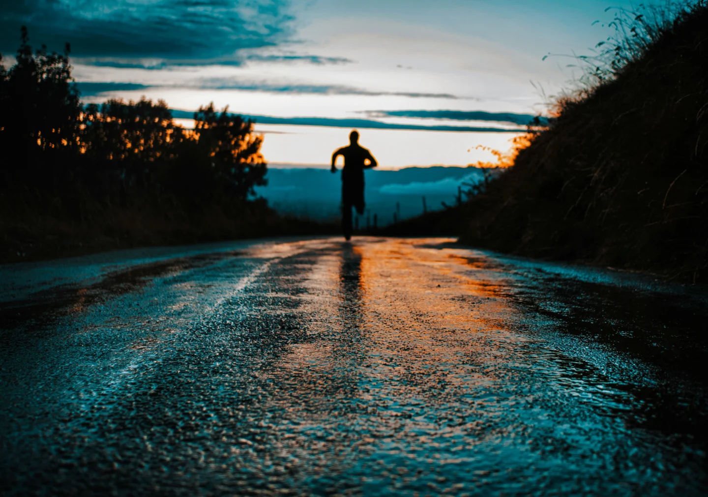 Silhouette of a runner at sunset on a wet road